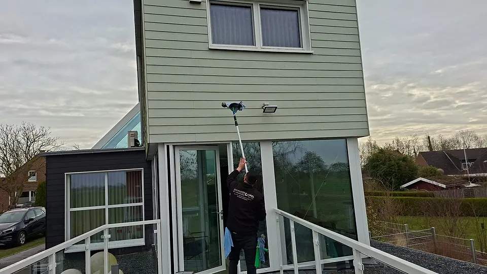 Mitarbeiter reinigt eine hohe Giebelverglasung mit der Teleskopstange