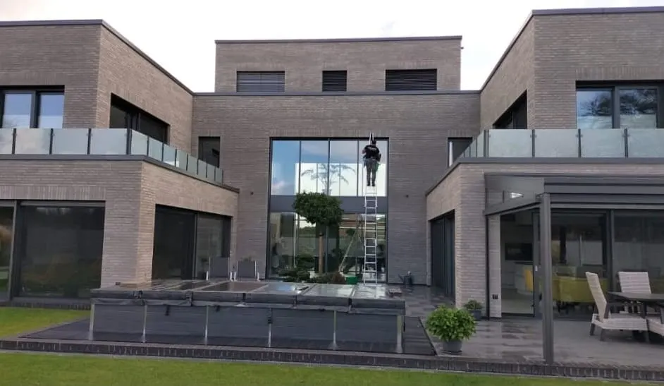 Mitarbeiter auf der Leiter an der hohen Glasfront eines modernen Wohnhauses